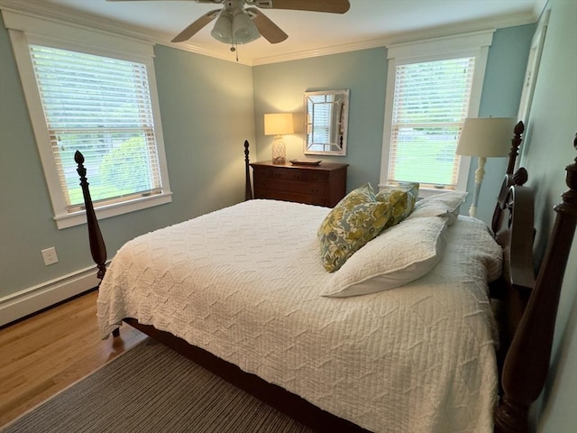 bedroom featuring wood finished floors, crown molding, a baseboard heating unit, ceiling fan, and baseboards