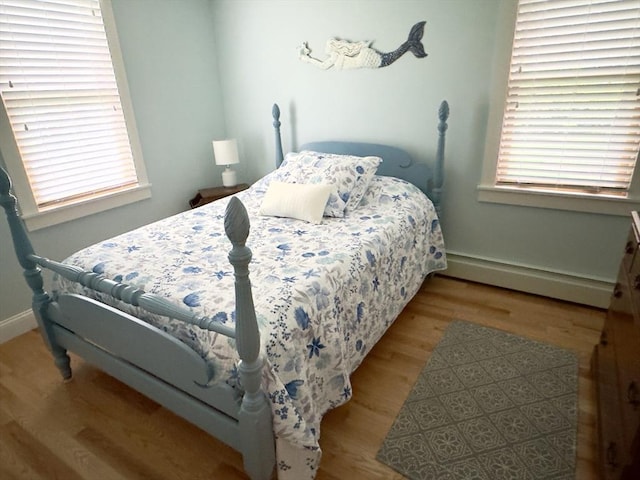 bedroom featuring baseboard heating, wood finished floors, and baseboards