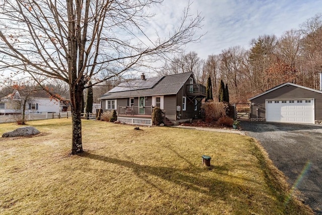 view of front of home with covered porch, a front yard, an outbuilding, a garage, and solar panels