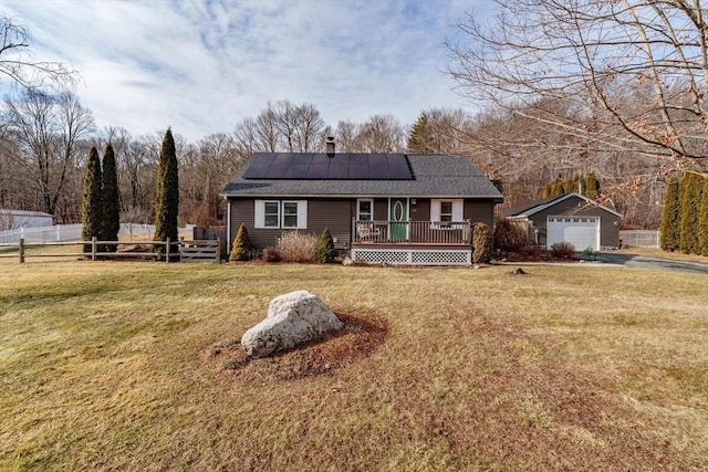 single story home with a garage, a front yard, an outbuilding, and solar panels