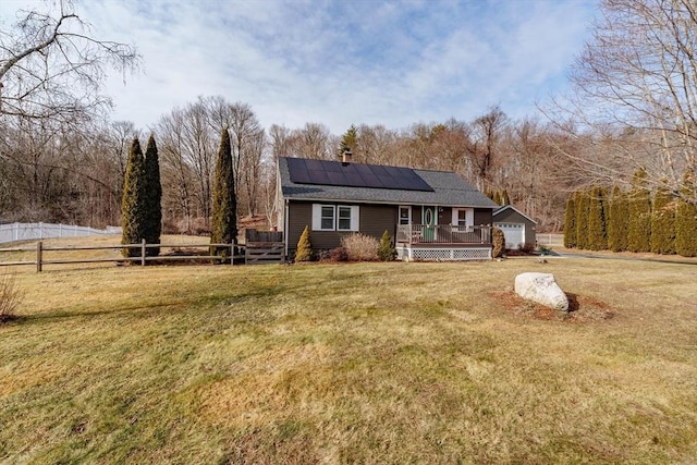 view of front of property with a garage, solar panels, a deck, and a front yard