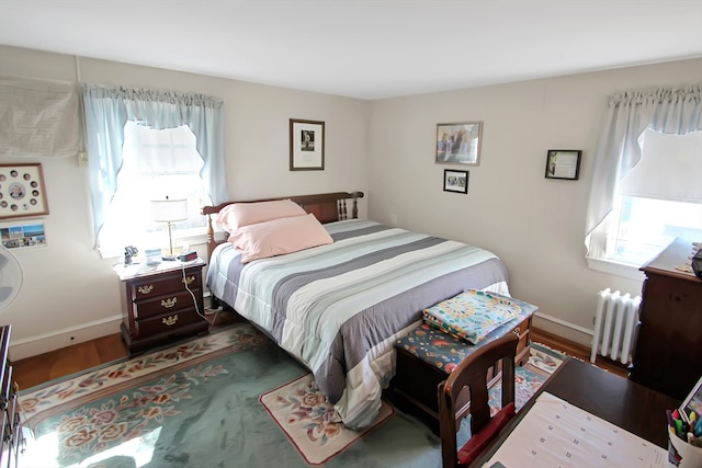 bedroom featuring radiator heating unit and hardwood / wood-style flooring