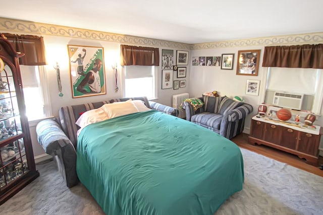 bedroom featuring cooling unit, radiator heating unit, and hardwood / wood-style floors