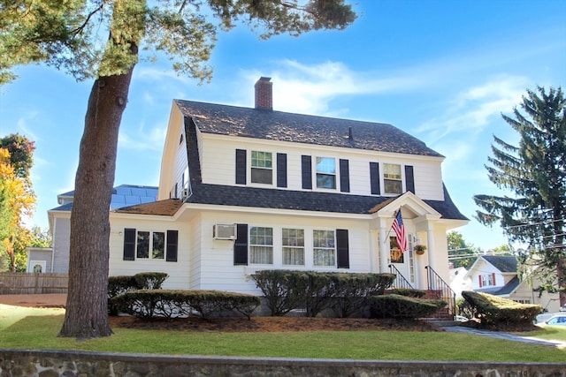 view of front of house featuring a front yard and an AC wall unit