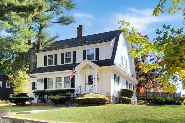 view of front of house featuring a wall mounted air conditioner and a front lawn