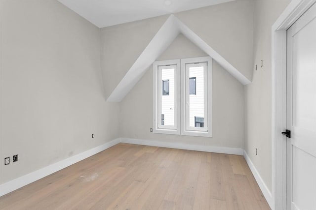 additional living space featuring vaulted ceiling and light hardwood / wood-style flooring