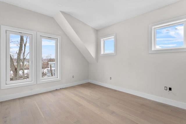 additional living space with vaulted ceiling and light wood-type flooring