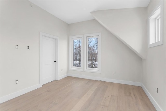 additional living space with light wood-type flooring and vaulted ceiling