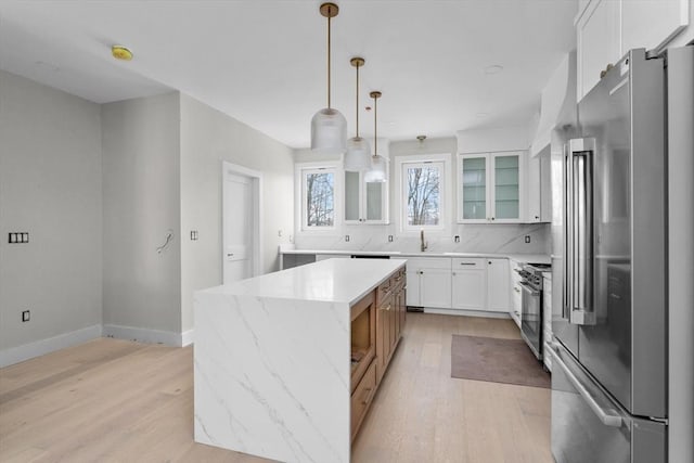 kitchen featuring a center island, light stone countertops, white cabinets, decorative light fixtures, and high quality appliances