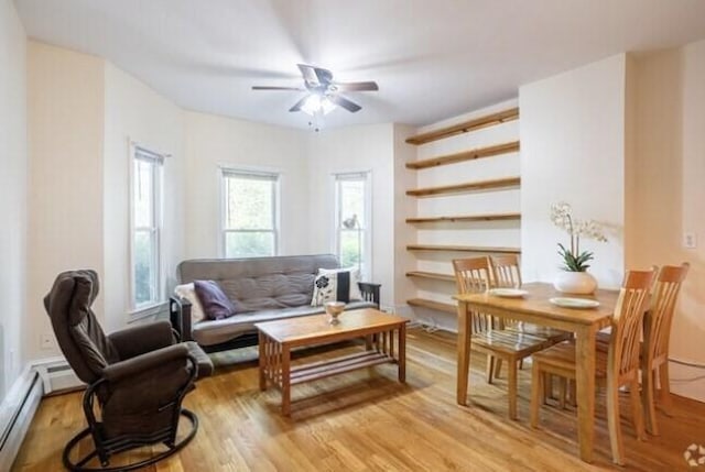 living area featuring a ceiling fan, light wood-type flooring, and baseboard heating