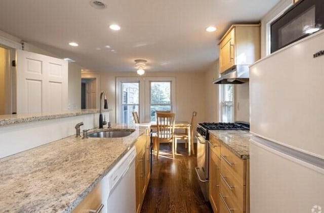 kitchen featuring white appliances, a sink, under cabinet range hood, recessed lighting, and dark wood-style floors