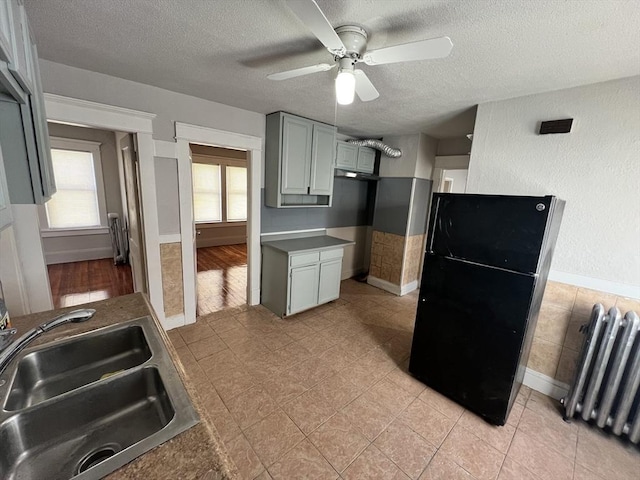 kitchen with freestanding refrigerator, a sink, a textured ceiling, and radiator heating unit