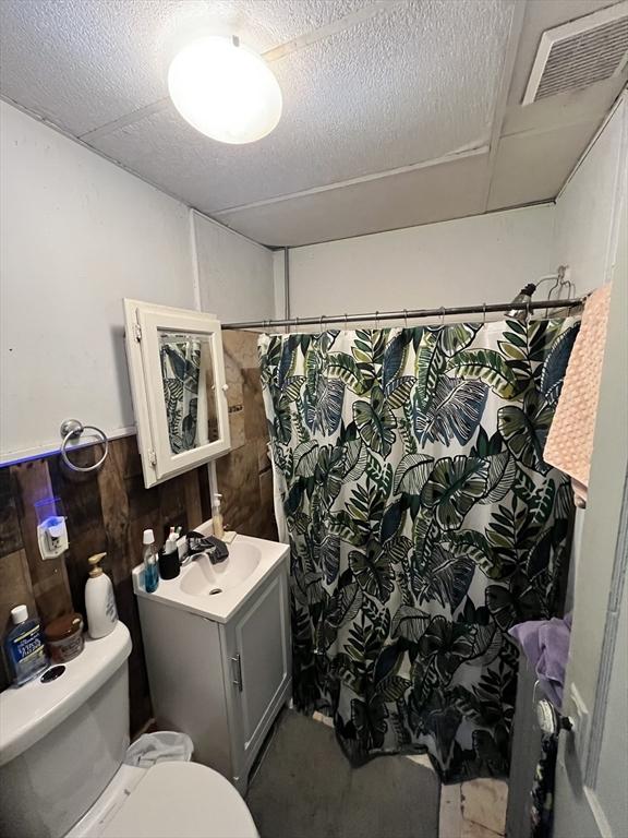 bathroom with toilet, a shower with shower curtain, vanity, and visible vents