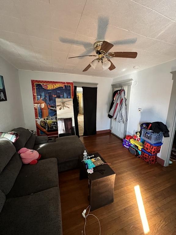 living area featuring wood finished floors, a ceiling fan, and baseboards