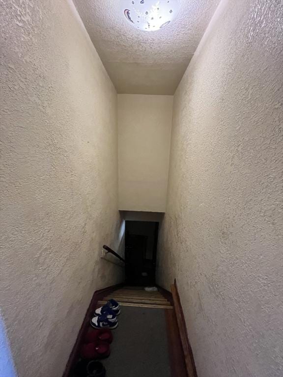 staircase featuring a textured wall and a textured ceiling