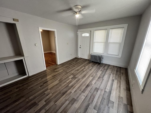 interior space featuring ceiling fan, a textured ceiling, dark wood-style flooring, baseboards, and radiator