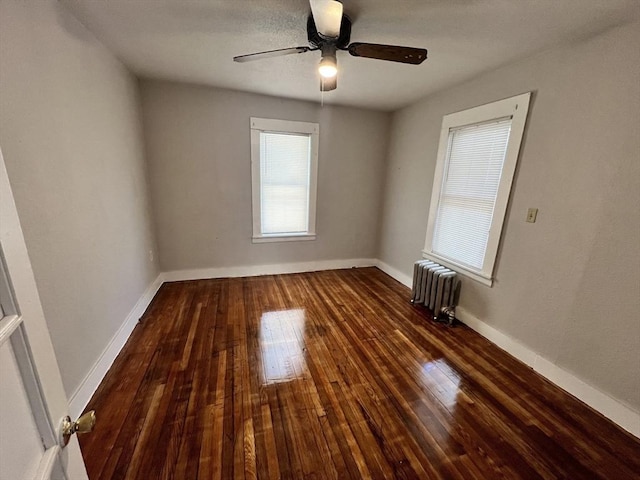 spare room with ceiling fan, radiator heating unit, baseboards, and wood-type flooring