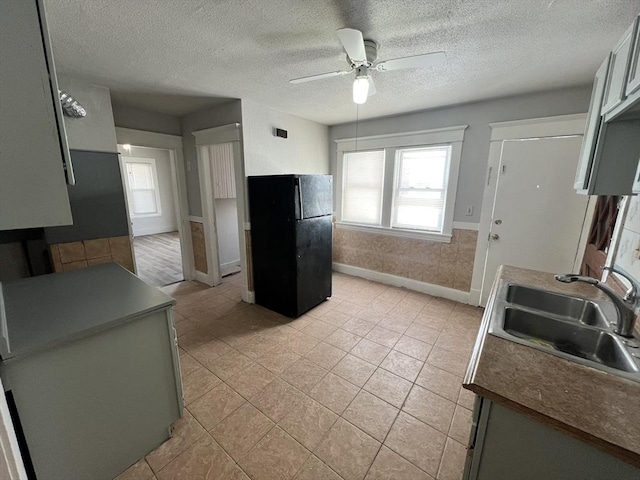 kitchen featuring a ceiling fan, dark countertops, freestanding refrigerator, a textured ceiling, and a sink