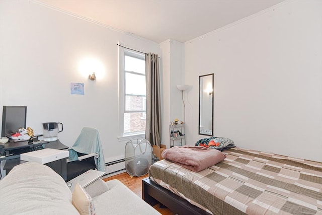 bedroom with multiple windows, a baseboard heating unit, and light wood-style floors