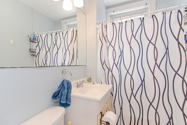 full bath featuring a shower with shower curtain, toilet, and vanity