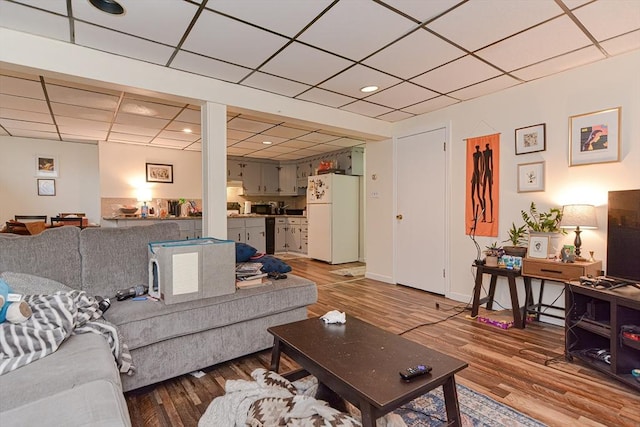 living room with a drop ceiling, baseboards, and wood finished floors