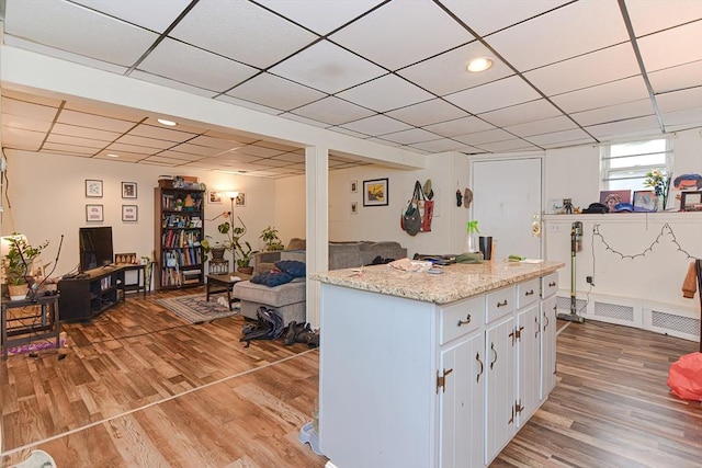 kitchen with a drop ceiling, light wood-type flooring, and white cabinetry