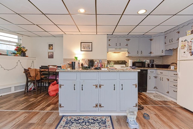 kitchen with light wood finished floors, decorative backsplash, black appliances, a paneled ceiling, and under cabinet range hood