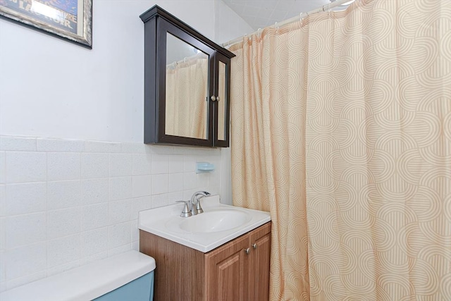 bathroom with toilet, vanity, and tile walls