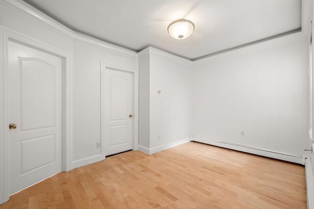 spare room with light hardwood / wood-style floors, a baseboard radiator, and ornamental molding