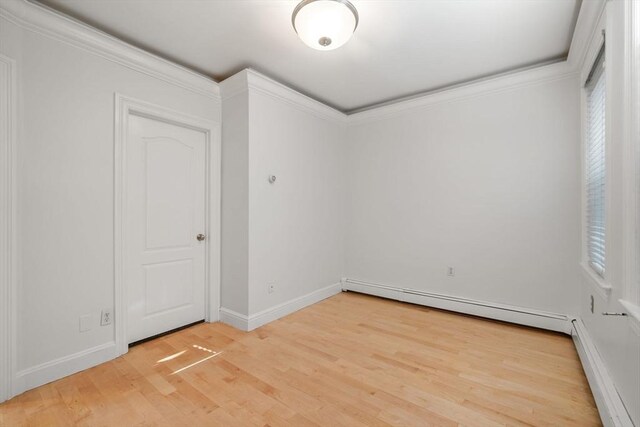 empty room with crown molding, light hardwood / wood-style floors, and a baseboard radiator