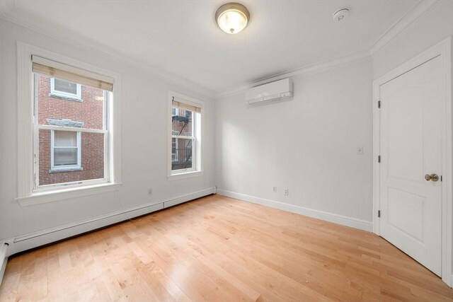 spare room with light hardwood / wood-style floors, baseboard heating, a wall mounted AC, and crown molding