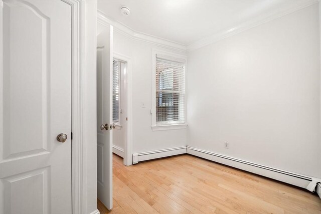 spare room with a baseboard heating unit, light hardwood / wood-style floors, and ornamental molding