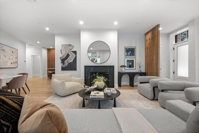 living room featuring recessed lighting, baseboards, light wood finished floors, and a fireplace