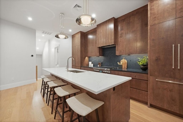 kitchen with visible vents, light wood-type flooring, a sink, and modern cabinets
