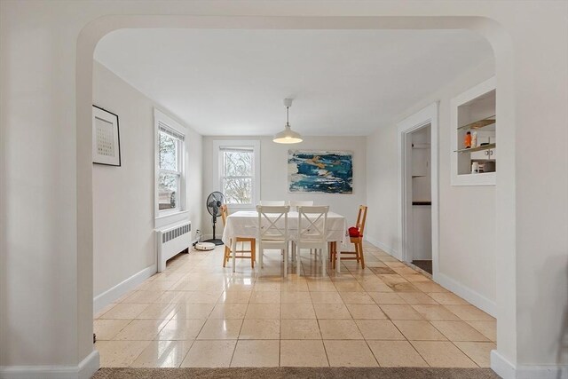 dining area with radiator, light tile patterned floors, baseboards, and arched walkways