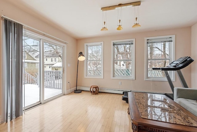 exercise area with a healthy amount of sunlight, light wood finished floors, and baseboards