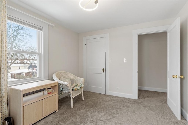 sitting room featuring light carpet, radiator heating unit, and baseboards