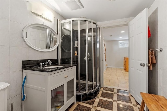 bathroom featuring a stall shower, tile walls, visible vents, and vanity