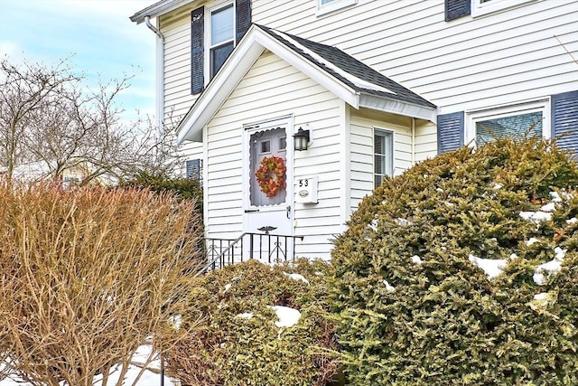 view of exterior entry featuring a shingled roof