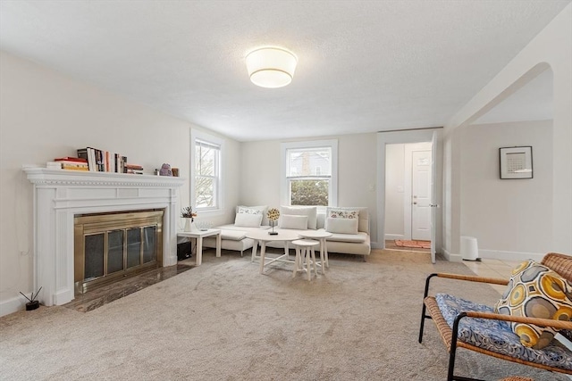 carpeted living room featuring a fireplace with flush hearth and baseboards