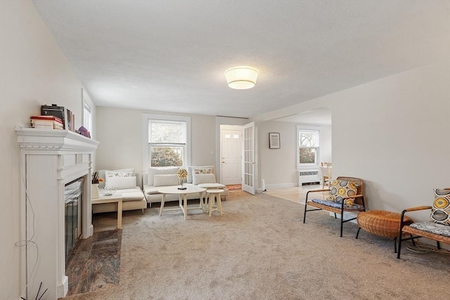 sitting room featuring arched walkways, a healthy amount of sunlight, carpet, and radiator