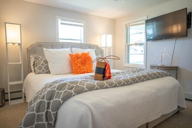 carpeted bedroom featuring multiple windows and baseboard heating