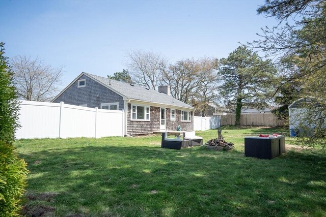 back of house with a lawn, a chimney, and a fenced backyard