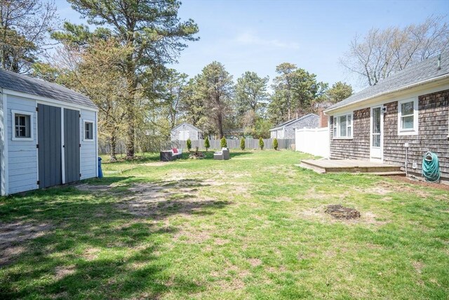 view of yard with a deck, fence, an outbuilding, and a shed