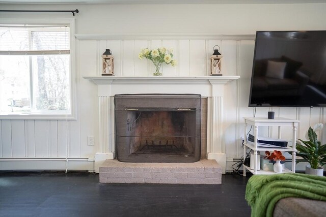 room details featuring a fireplace, a baseboard heating unit, and wood finished floors