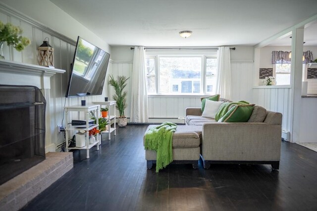living area with dark wood-type flooring, a baseboard radiator, and a healthy amount of sunlight