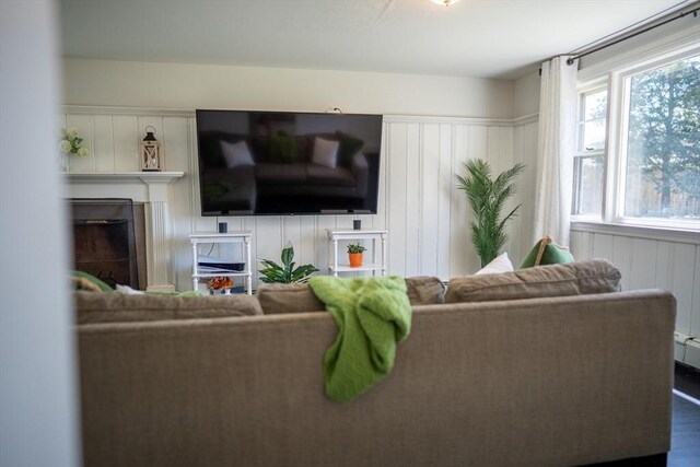 living room with a decorative wall, dark wood-style floors, and a fireplace