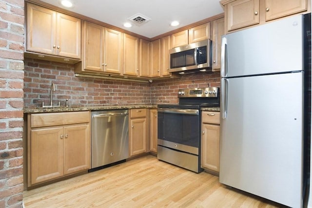 kitchen with light wood-style floors, light brown cabinets, appliances with stainless steel finishes, and a sink