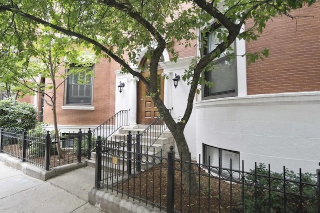 property entrance featuring brick siding and fence