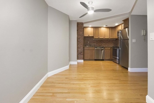 kitchen with a ceiling fan, light wood-type flooring, baseboards, backsplash, and appliances with stainless steel finishes